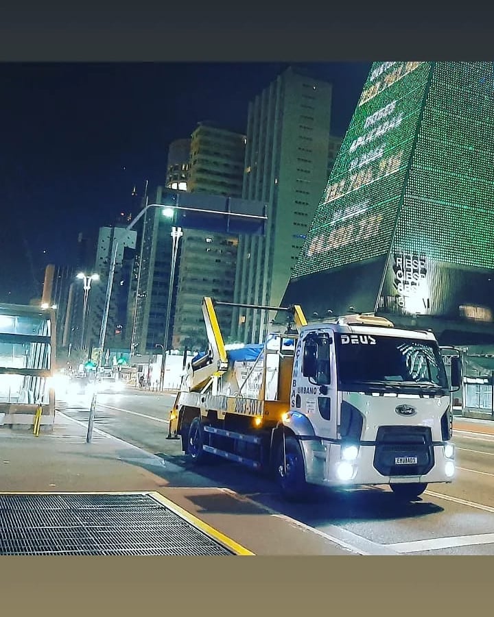 Caminhão da Urbanos Caçambas transportando caçamba amarela na Avenida Paulista, São Paulo